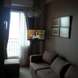 sala de estar con sofá y TV en Apartemen Ciumbuleuit 2, en Bandung