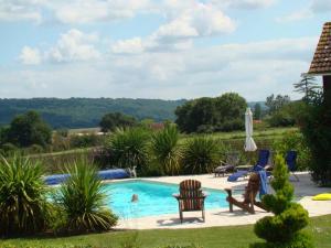 a swimming pool with two chairs and a umbrella at Country Farmhouse with pool in Lascazères +29 photos
