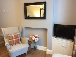 a living room with a tv and a chair and a mirror at Brampton Holiday Cottage in Brampton