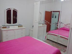 a pink bedroom with two beds and a mirror at Terrazza Sul Mare in Gioiosa Marea
