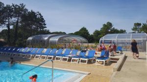 a swimming pool with chairs and people in the water at Mobil-home Confort camping le bois Masson in Saint-Jean-de-Monts