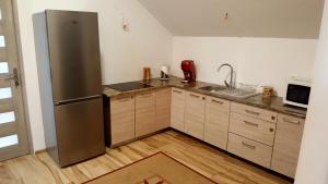 a kitchen with a stainless steel refrigerator and wooden cabinets at Apartamenty Daisy in Goczałkowice-Zdrój