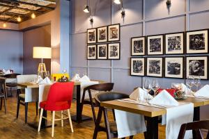 アラドにあるibis Styles Aradの壁に絵画が飾られたテーブルと椅子のあるレストラン