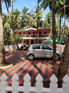 a car parked in front of a house with palm trees at Hilias Retreat in Palolem
