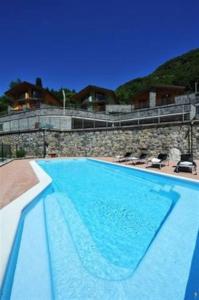 a large blue swimming pool with chairs and a building at Villa Orchidea With Pool in Varenna