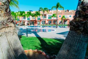 uma vista para uma piscina com palmeiras e um edifício em Moradia Jardins do Vale em Albufeira