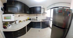 a kitchen with black cabinets and a stainless steel refrigerator at Cusco Mágico 4 - Departamento Las Torres Kayser in Cusco