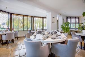 a dining room with tables and chairs and windows at Hôtel Restaurant Des Remparts in Chaumont