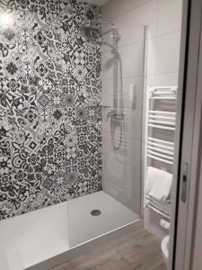baño con ducha y papel pintado en blanco y negro en Hôtel Royal, en Montpellier