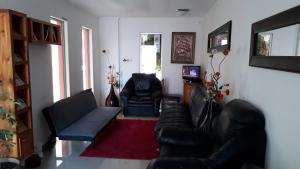 een woonkamer met 2 leren stoelen en een bank bij Apart Hotel Colors in La Serena