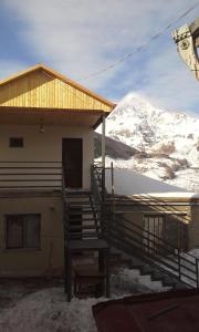 una casa con una scala di fronte a una montagna di Guest House Sunset a Kazbegi