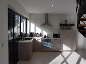 Una cocina con gabinetes blancos y un horno de estufa. en Le lodge, en Vaux-sur-Mer