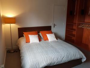 Un dormitorio con una cama con almohadas naranjas y blancas. en Le lodge, en Vaux-sur-Mer