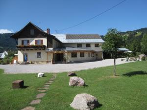 a house with rocks in the grass in front of it at Pension Lipicer in Kötschach