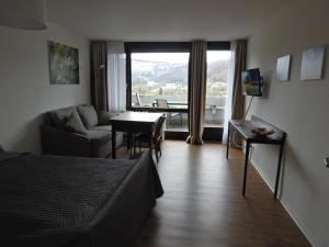 a living room with a couch and a table and a room with a window at FREE Apartment - Schönblick in Bad Urach