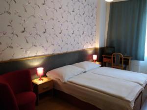1 dormitorio con 1 cama y 1 silla roja en Penzion Vis a Vis en Třebíč
