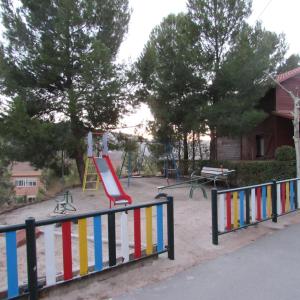 einen Spielplatz mit einer roten Rutsche und einer Schaukel in der Unterkunft Camping-Bungalows Ciudad de Albarracín in Albarracín