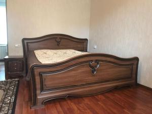 キスロヴォツクにある2-ух комнатная квартира в центре городаのウッドフロアの客室で、大型の木製ベッド1台が備わります。