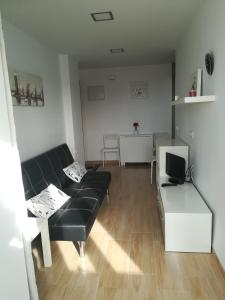 ein Wohnzimmer mit einem schwarzen Sofa und einem Tisch in der Unterkunft Bay Home in Cádiz