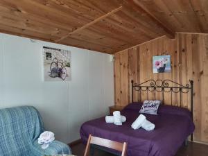 1 dormitorio con 1 cama de color púrpura y 1 silla en Camping Ruta del Purche, en Monachil