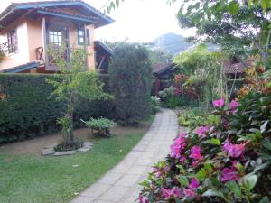 a garden with pink flowers in front of a house at Pousada Arte de Viver in Lumiar