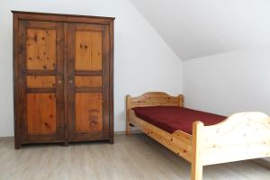 1 dormitorio con 1 cama y armario de madera en Ferienwohnung I en Schnelldorf