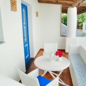 サンタ・マリーナ・サリーナにあるSalinArteの白いテーブルと椅子、青いドアが備わる客室です。