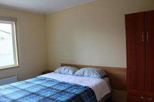 a bedroom with a bed with a blue plaid blanket at Hostal Lagunitas in Puerto Montt