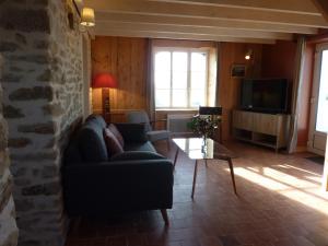 a living room with a couch and a tv at Le Pilleur d'Epaves in Cléden-Cap-Sizun