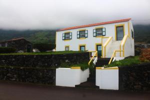 ein Haus auf einem Hügel mit einer Steinmauer in der Unterkunft Casa dos Felicias in São Roque do Pico