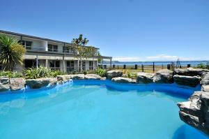 a large pool with blue water in front of a house at Wai Ora Lakeside Spa Resort in Rotorua