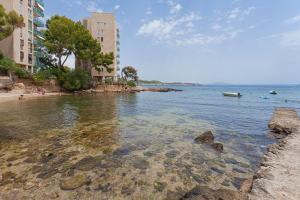 a beach with rocks in the water next to buildings at Ses Gerres Beach House in Illetas