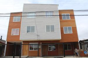 a house with a fence in front of it at Hostal ViBeMontt in Puerto Montt