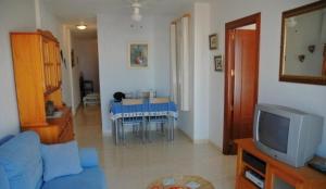 a living room with a blue couch and a tv at One-bedroom flat 200m from the beach in Almería