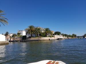 a boat on a river with palm trees and buildings at Appartement Costa brava in Roses