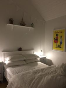 a bedroom with a white bed and a picture on the wall at The Old Beach Cottage, Achill in Doogort