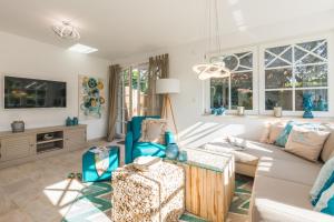 a living room with a white couch and blue chairs at Ferienhaus Ostseehaus Seegras mit Kamin in Prerow
