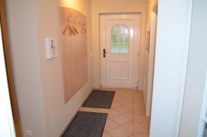 a hallway with a white door and two rugs on the floor at FH Bernstein in Ostseebad Karlshagen
