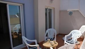 One-bedroom flat 200m from the beach في ألميريا: غرفة بها كراسي بيضاء وطاولة