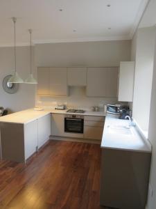 uma cozinha com armários brancos e piso em madeira em Barclay House em Kelso