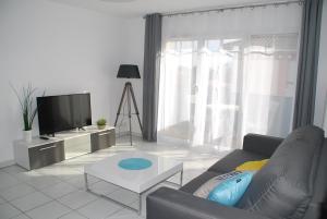 a living room with a couch and a tv at Comme à la maison in Gujan-Mestras