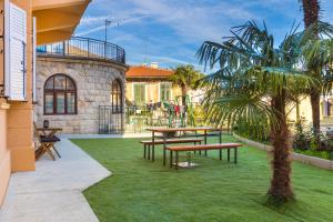 a patio with picnic tables and a palm tree at Apartment Fiorentina in Opatija