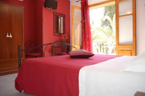 a red bedroom with a bed with a red blanket at Sunrise in Lascari