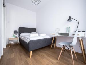 a bedroom with a bed and a desk and a chair at Emihouse CityVibe Apartments in Rzeszów