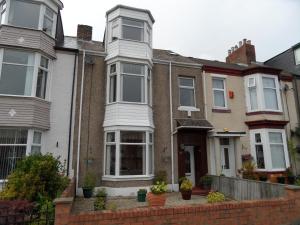 a house with white windows and a brick fence at St Georges sea view in Sunderland
