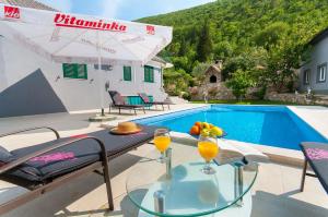 - une table avec des boissons à côté de la piscine dans l'établissement Apartments Srdanovic, à Omiš
