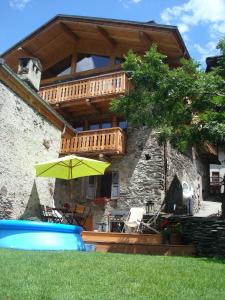 a house with a balcony and an umbrella in the yard at Chalet Marron by Tarentaise Properties in Sainte-Foy-Tarentaise