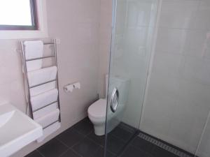 a white bathroom with a toilet and a shower at Augathella Motel & Caravan Park in Augathella
