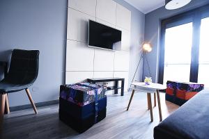 ein Wohnzimmer mit einem Sofa und einem TV an der Wand in der Unterkunft DesignOmania Apartments - Przedwiośnie 2A in Krakau