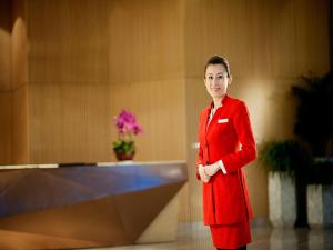 Una mujer con un traje rojo parada en una habitación en Wyndham Grand Qingdao en Huangdao